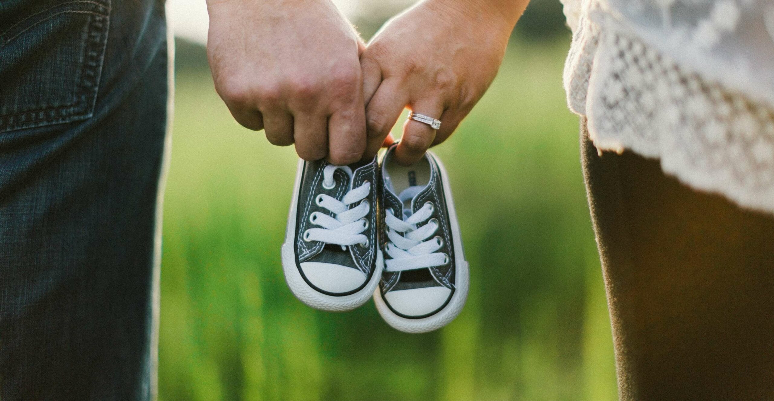 Partnerschaften Ehepaar hält gemeinsam Kinderschuhe