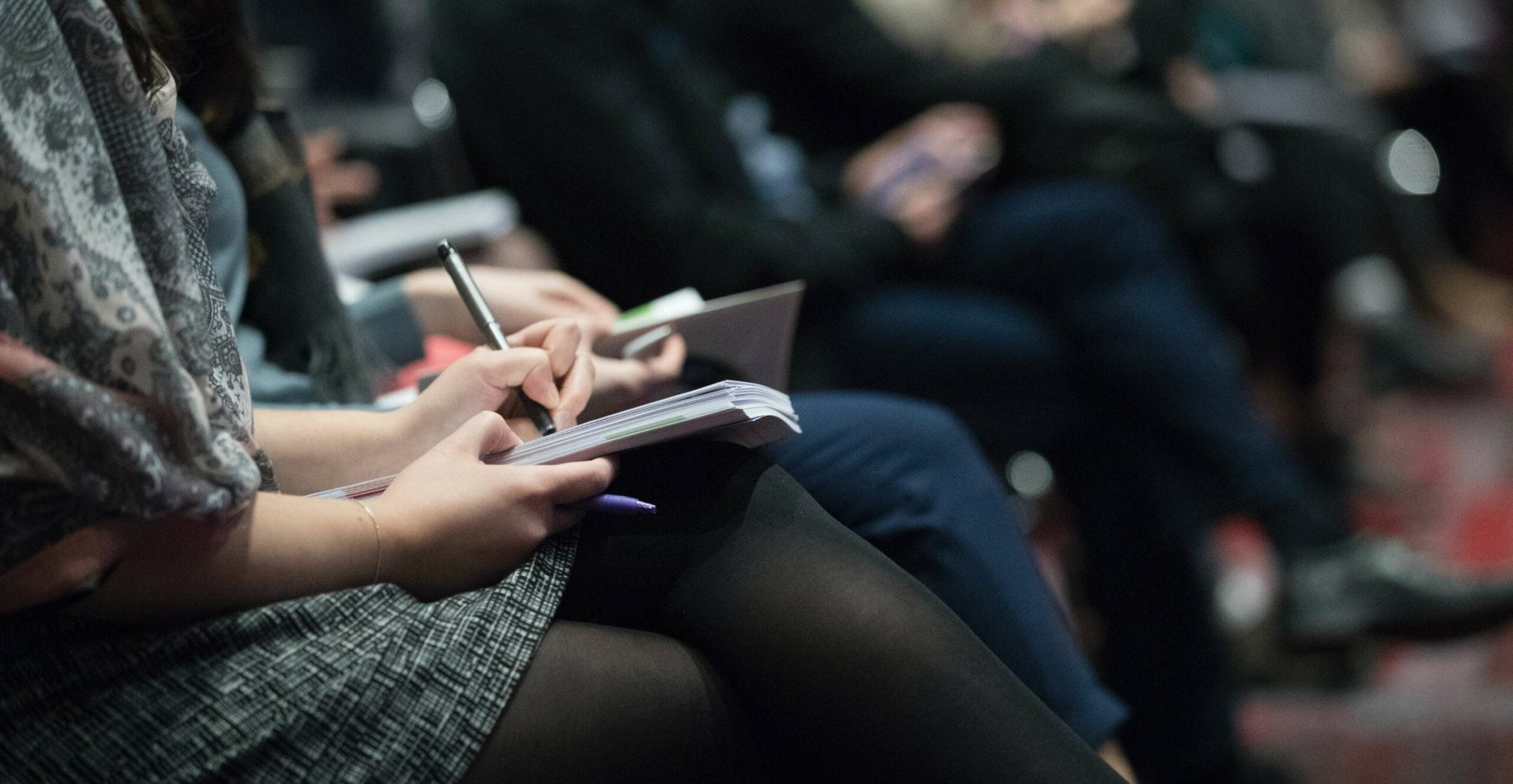 Vortrag: Personen schreiben bei einem Elternabend mit